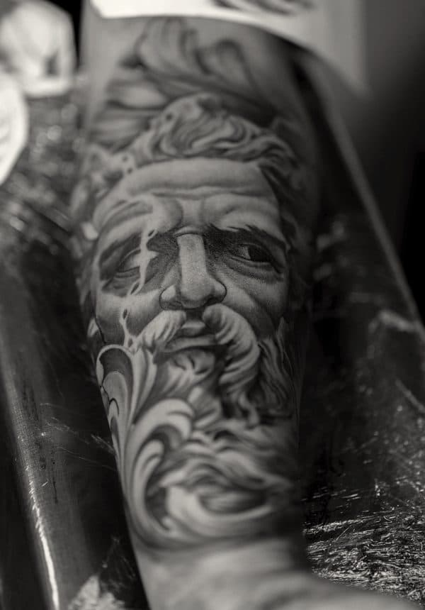 black and grey portrait of a bearded figure on a forearm