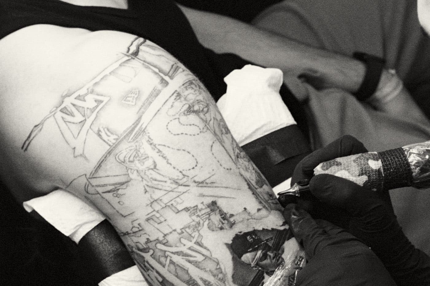 an artist tattooing a client's arm, machine in hand